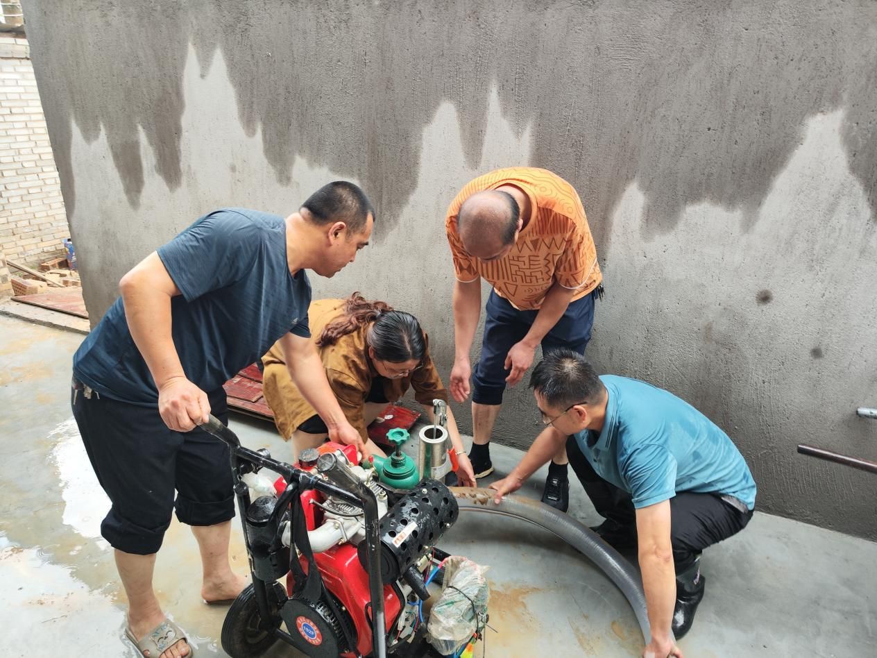 王小丽（左二）与应急志愿服务队队员用抽水泵清理居民家中倒灌积水