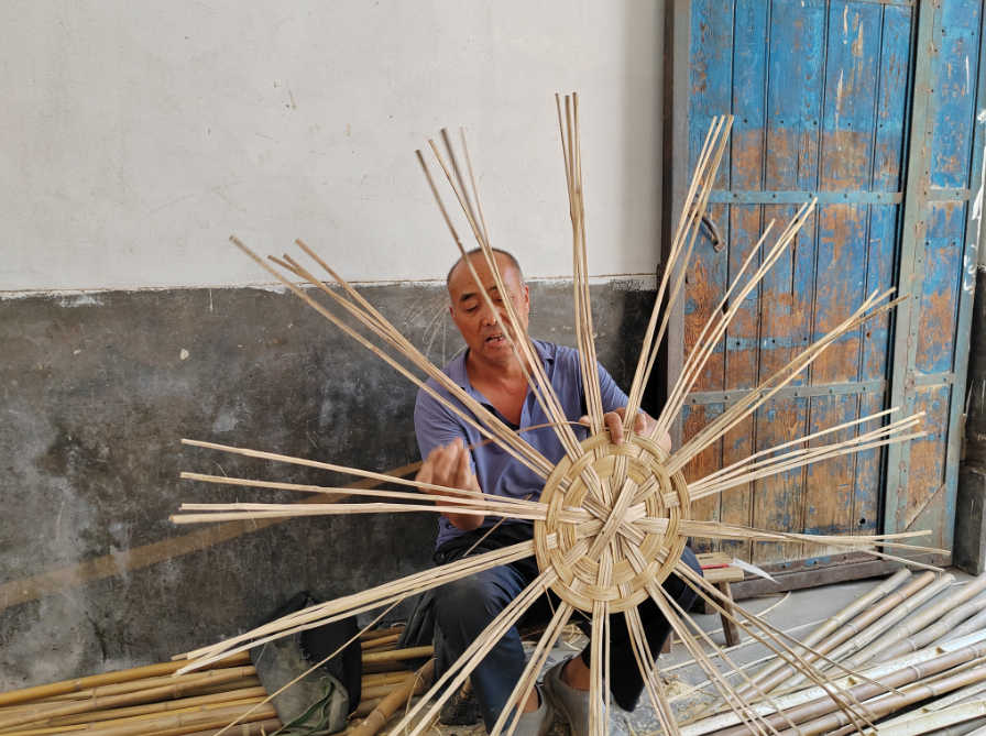 蔺恩虎正在编竹筐（本文图片由华阴市岳庙街道办事处提供）
