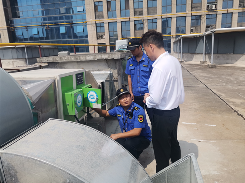 执法队员查看油烟在线监控设备数据