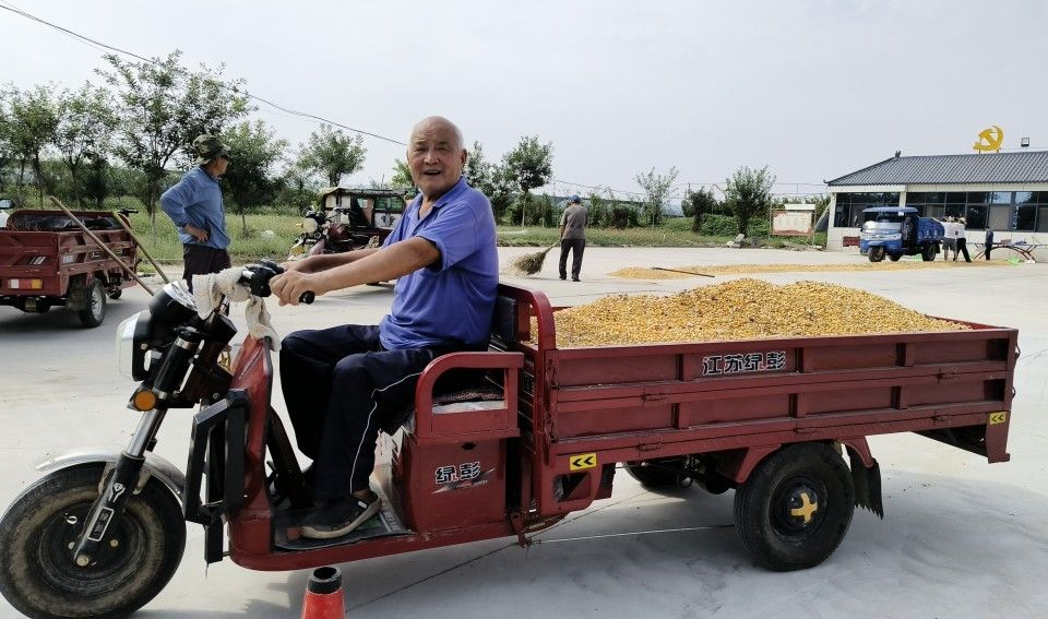 村民用三轮车把玉米运送到村部广场