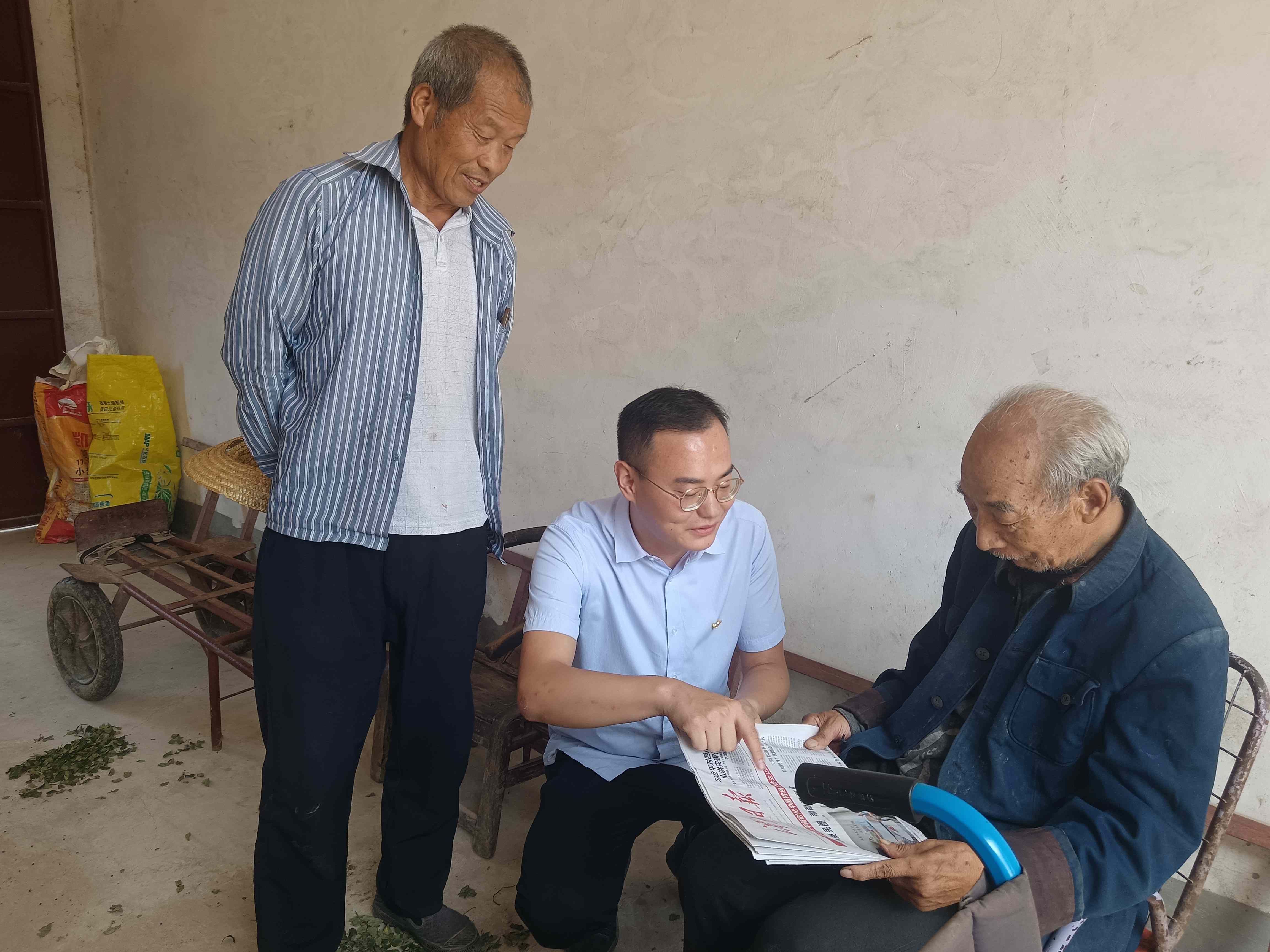 村干部(图左)及第一书记(图中)同老党员拉家常、送读上门