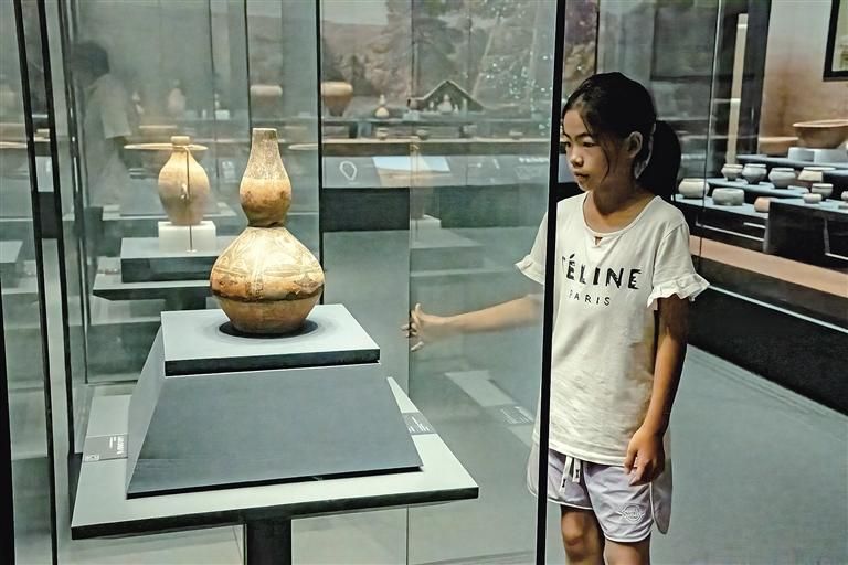 8月8日，一名小学生在铜川博物馆欣赏人面纹彩陶葫芦瓶。