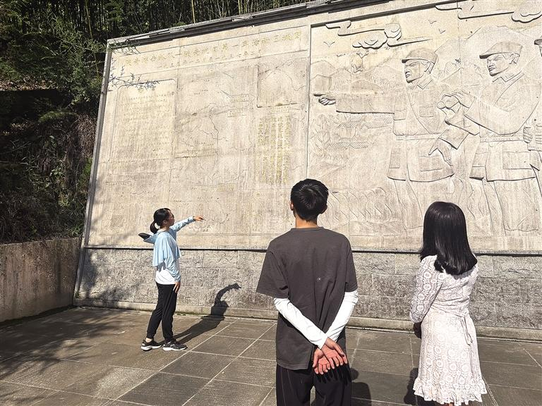 8月19日，陕南人民抗日第一军纪念碑后的浮雕墙前，讲解员向游客讲述革命故事。记者 齐珂雨 摄