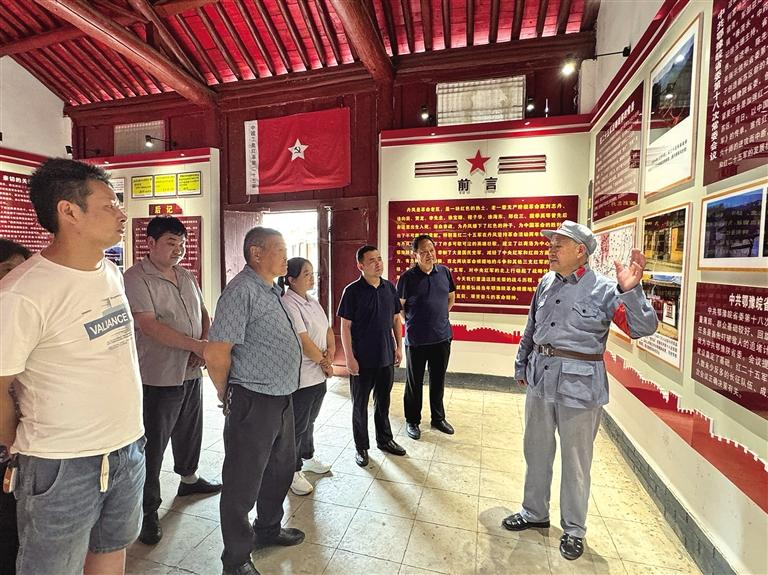 8月19日，丹凤县庾岭镇鄂豫皖省委常委会议旧址内，杨青山（右）为游客讲解。记者 文超 摄