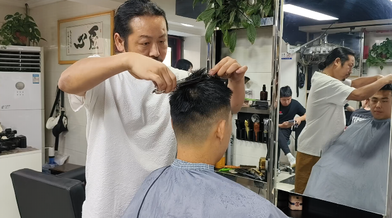 店主胡志波正在为来自咸阳的参赛球员郭龙修剪头发